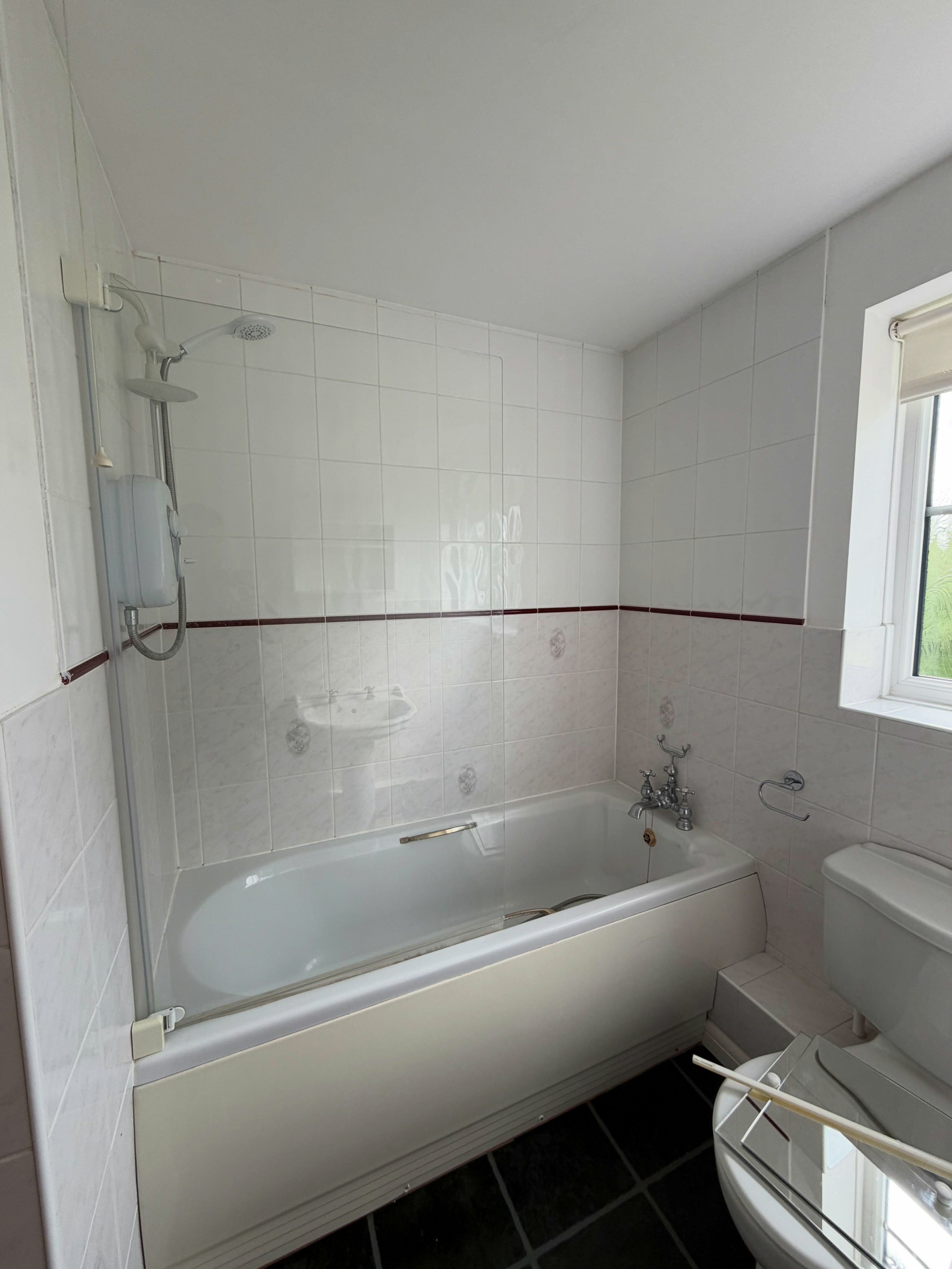 Bathroom before renovation with white bath, wall tiles and original fittings.