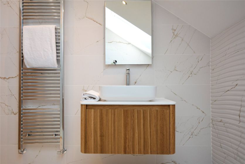 A modern attic bathroom vanity featuring a Wish ribbed natural oak wall-hung unit with an Ibecko white countertop basin, Dune marble-effect 4D tiles, and a Lemer motion-sensor LED mirrored cabinet.