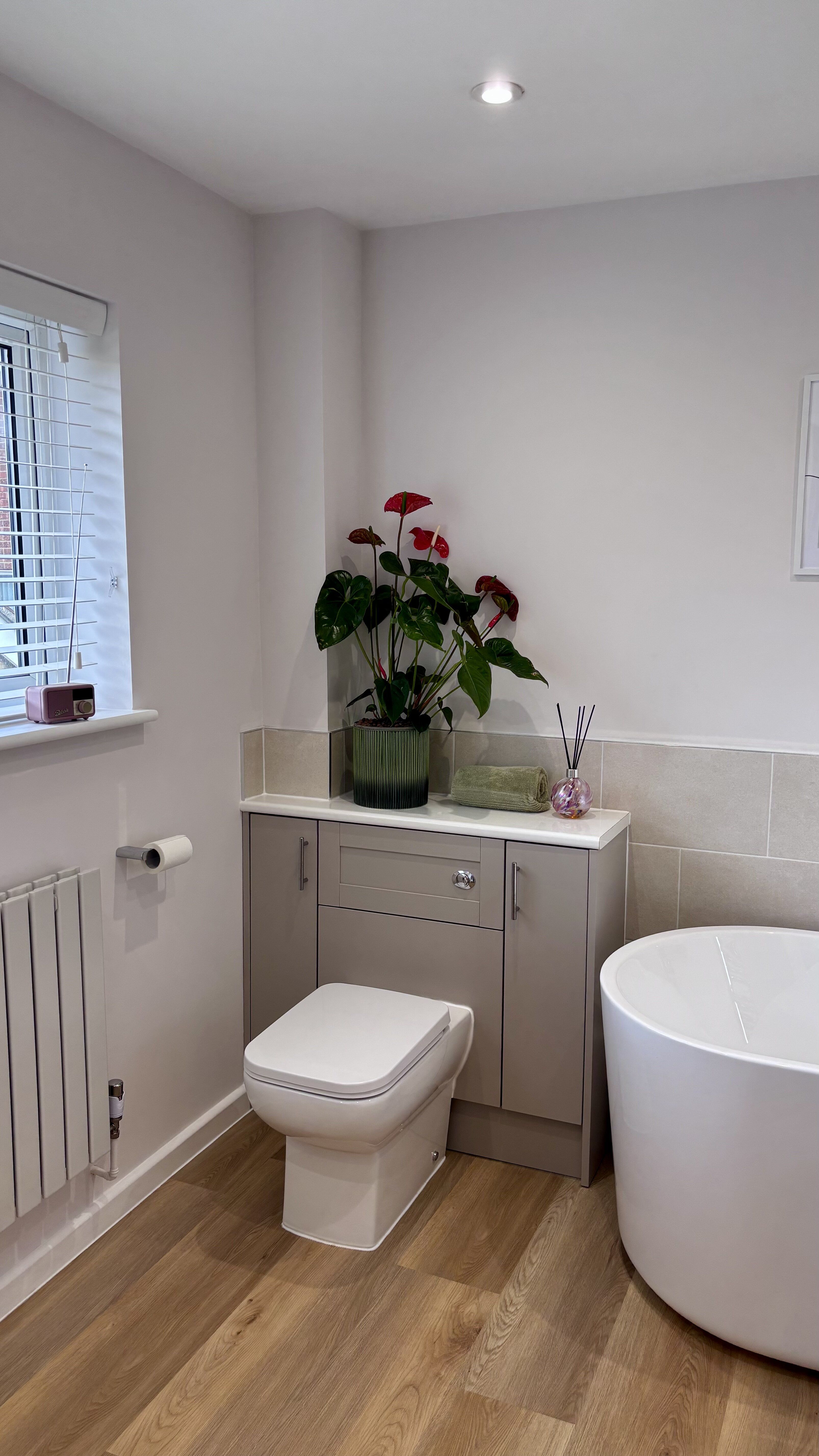 Bathroom display at Easy Bathrooms Ipswich featuring a freestanding bath, wall-hung toilet and warm wood-effect flooring.
