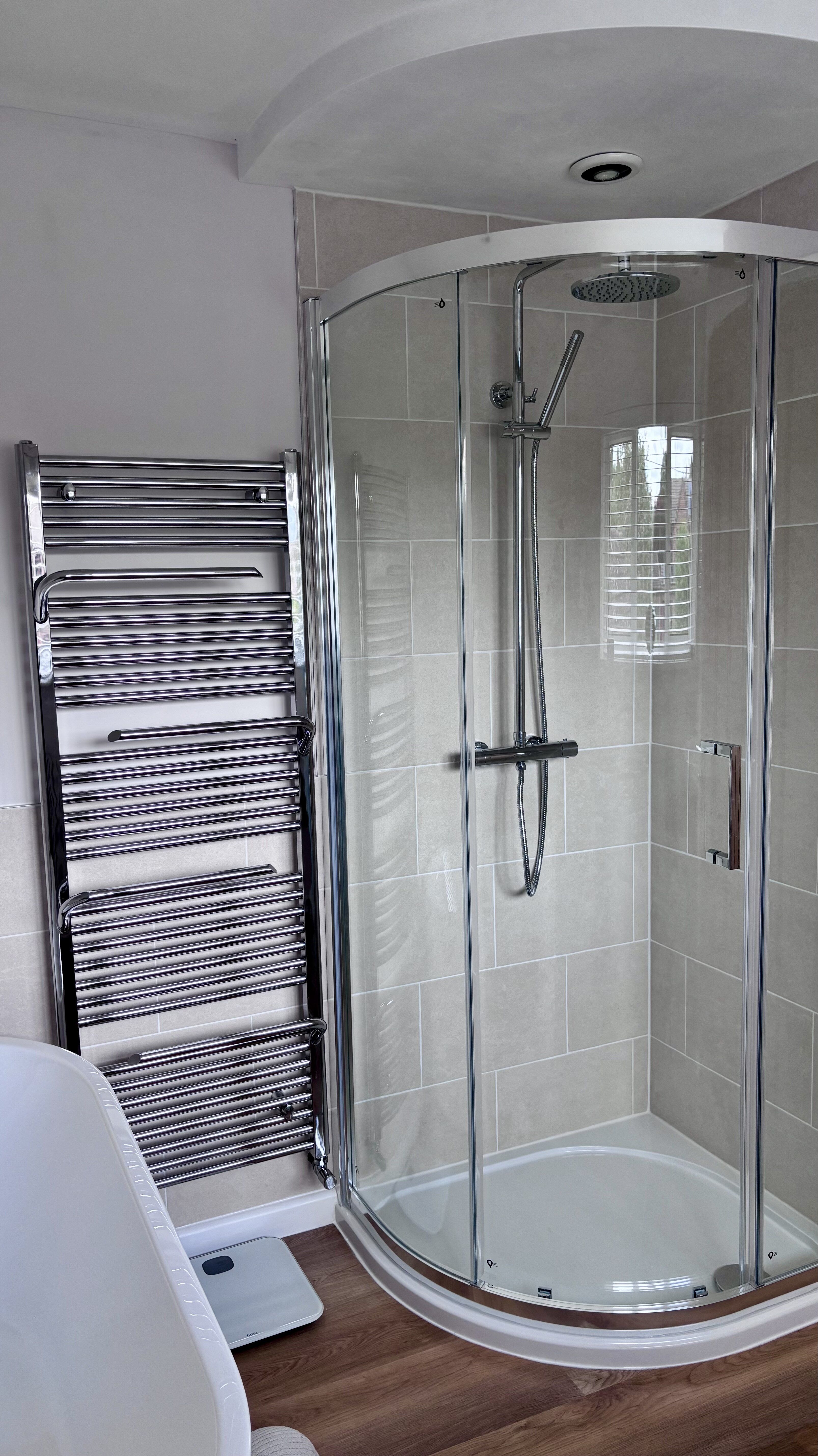 Quadrant shower enclosure with chrome fittings and heated towel rail in the Ipswich showroom display.