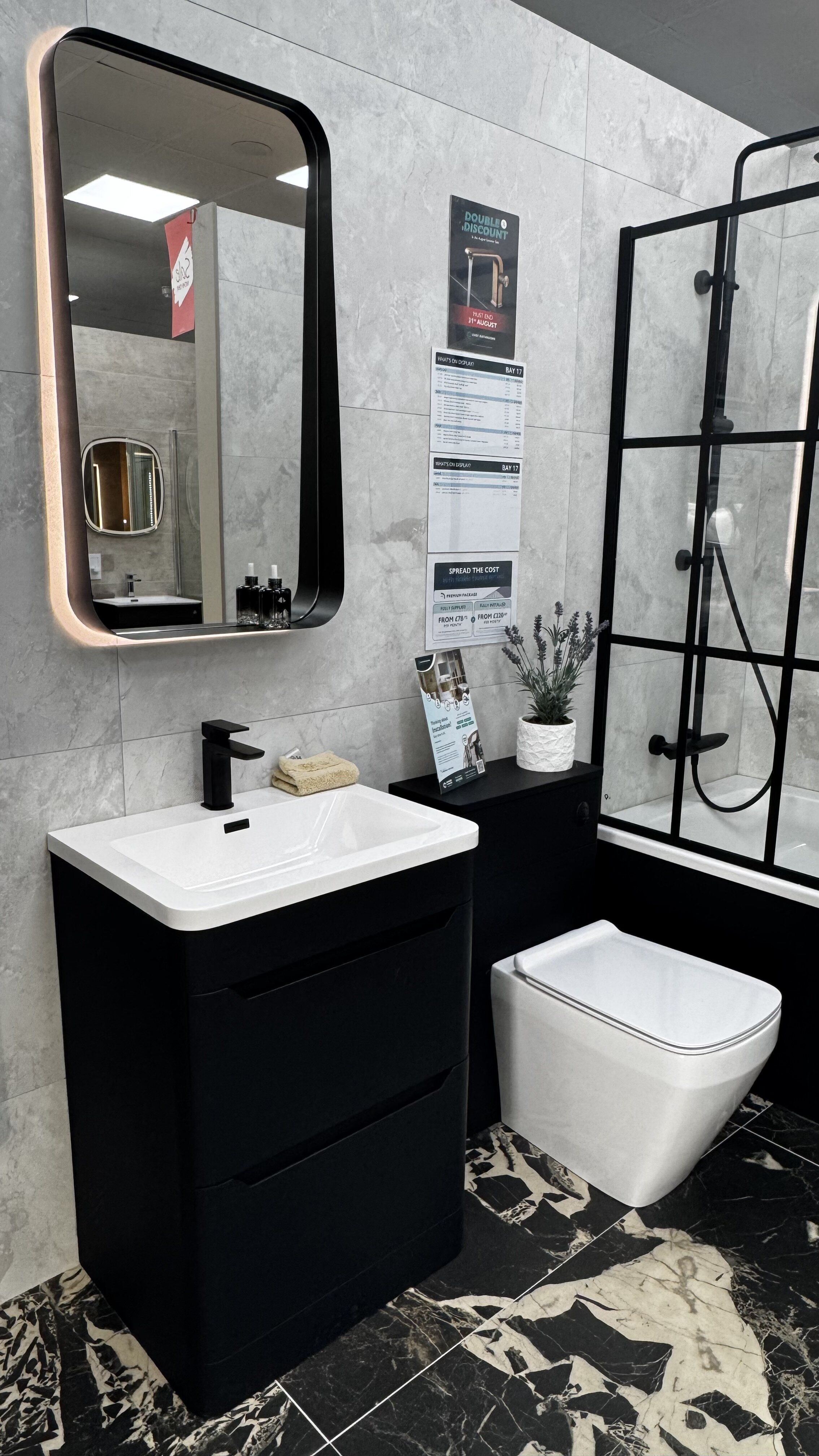 New bathroom display at Easy Bathrooms Leeds Seacroft with black furniture, illuminated mirror, toilet and framed shower screen.