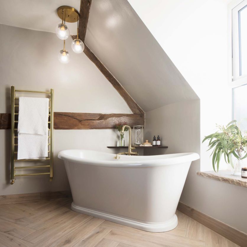Darcey freestanding soaking tub and Urban gold mixer set against herringbone Wendu Taupe wood effect flooring.