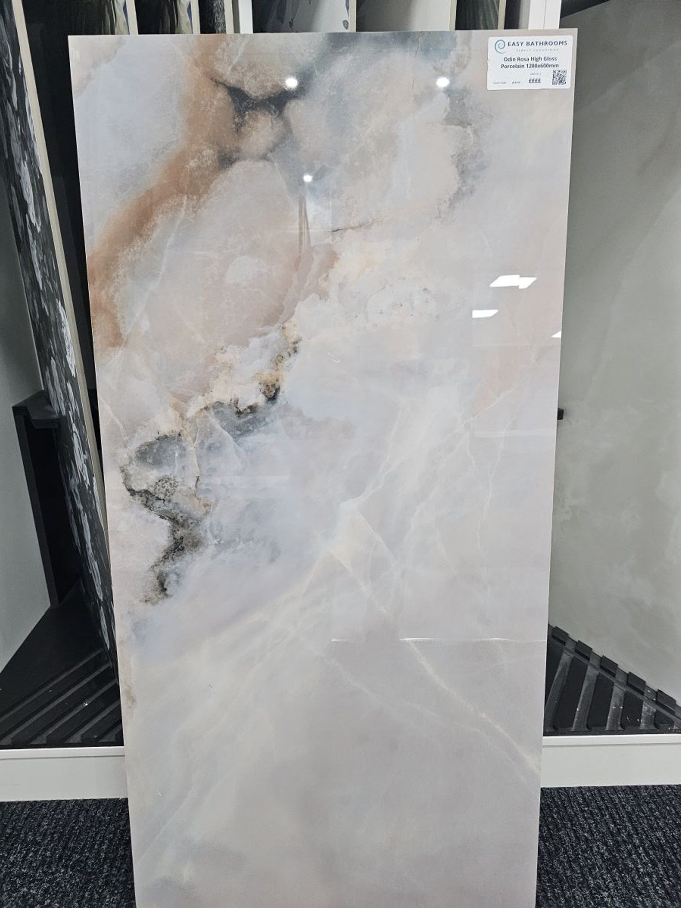 Large glossy marble-effect porcelain tile sample with soft grey, cream and warm veining.