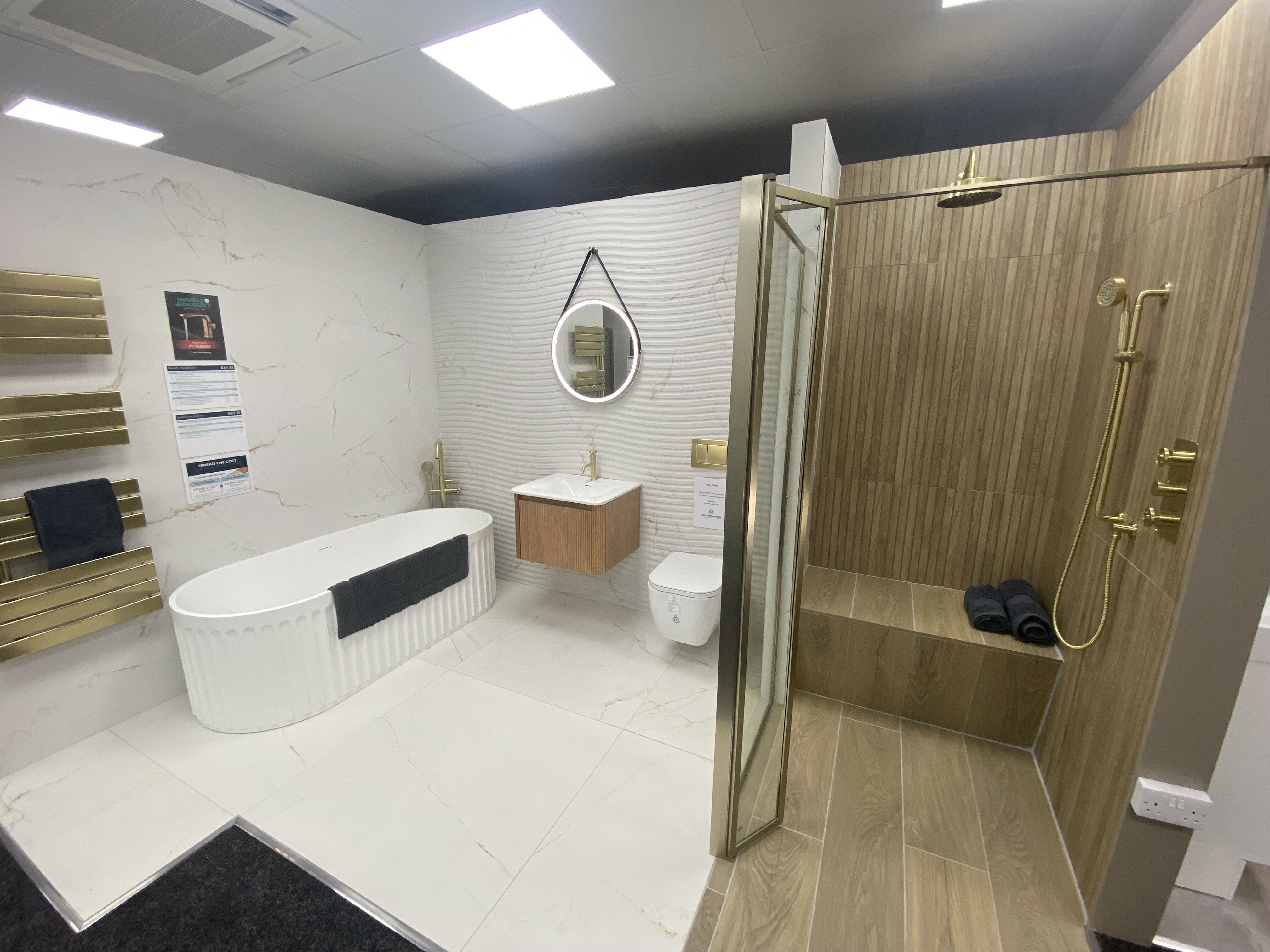 New bathroom display at Easy Bathrooms Newbury featuring warm wood furniture, neutral finishes and modern lighting.