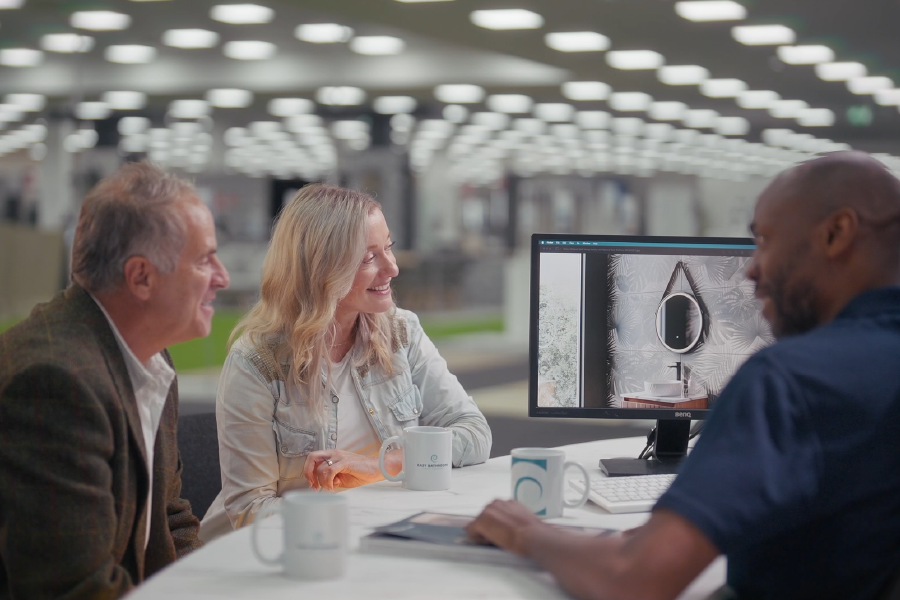 Customers viewing a 3D bathroom design with a showroom designer during an in-store consultation.