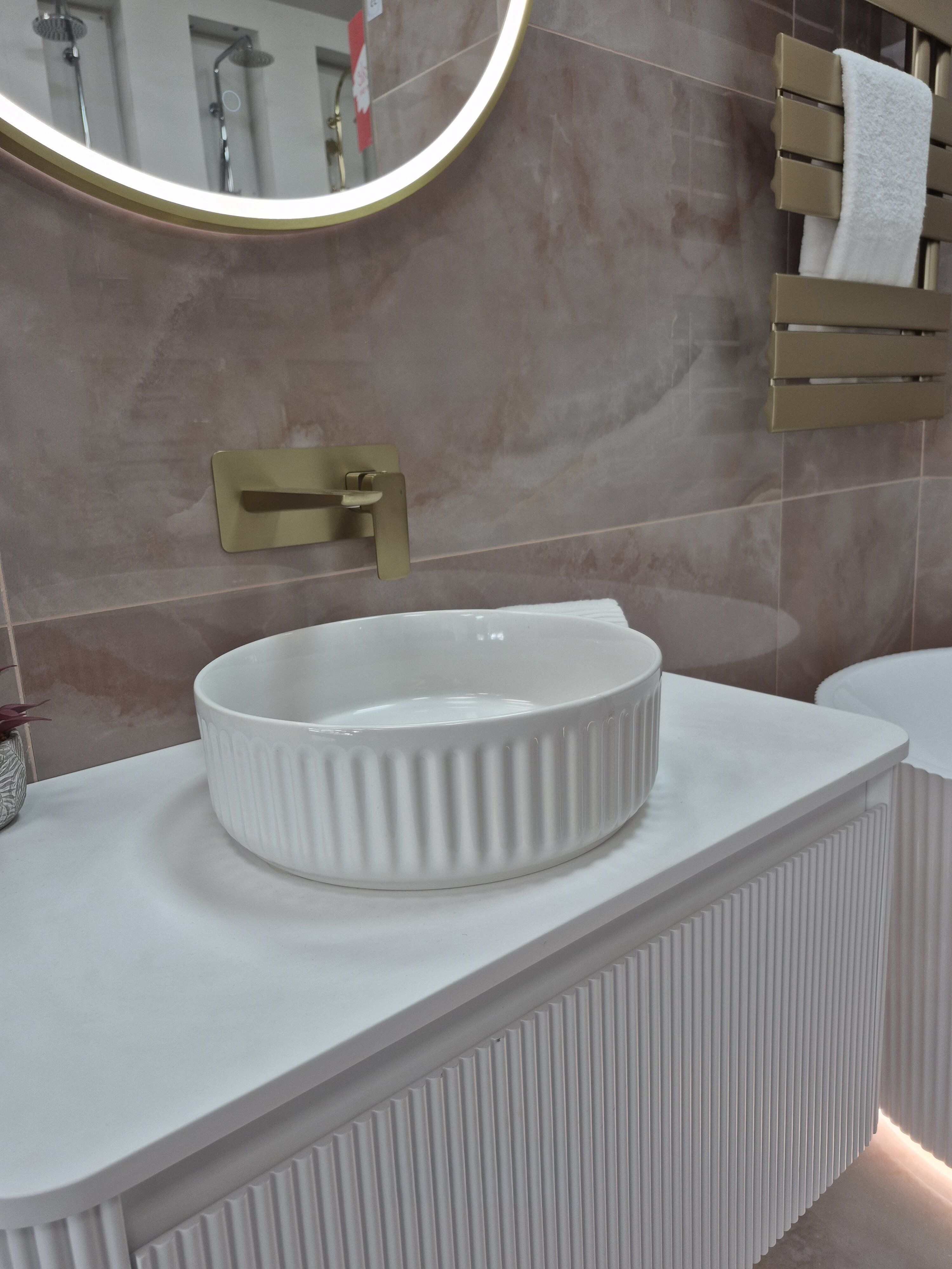 White countertop basin with fluted detailing and brushed gold tap within the pink Doncaster bathroom display.