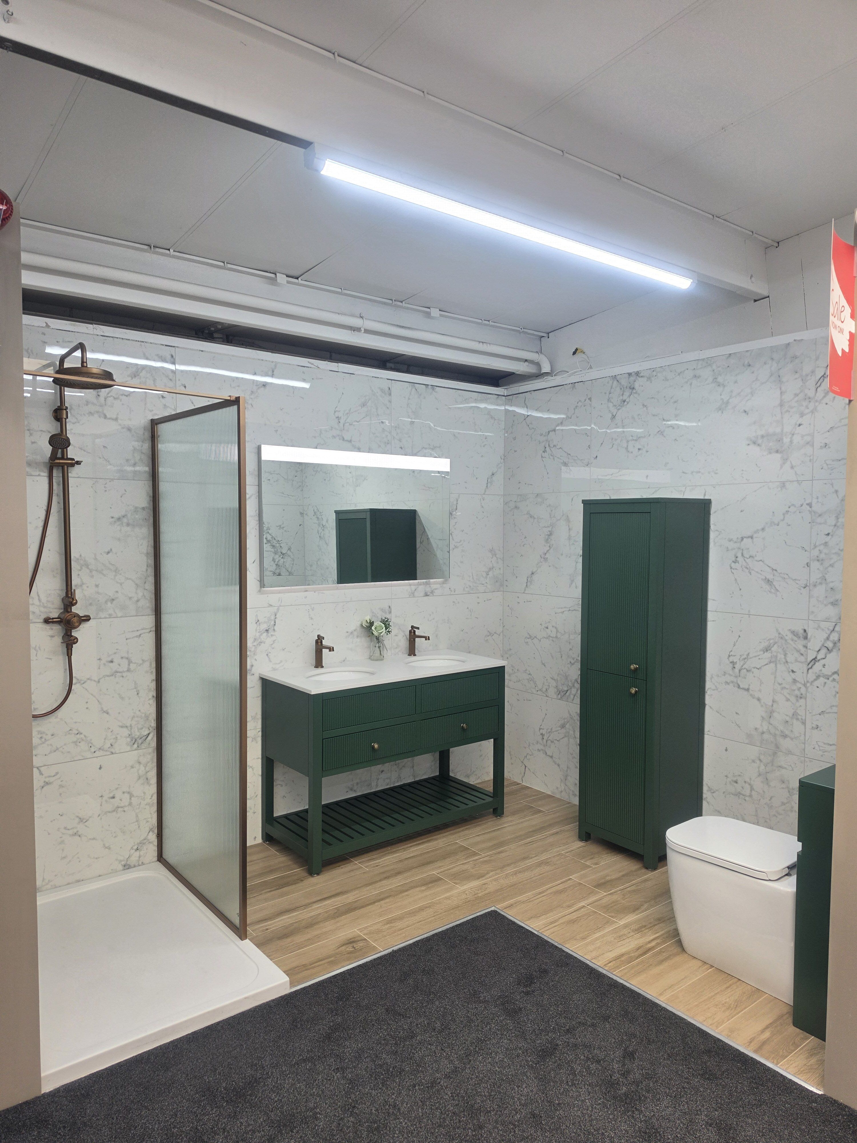 bathroom display in Farnborough Easy Bathrooms featuring large format marble tiles, green bathroom furniture and brushed bronze hardware