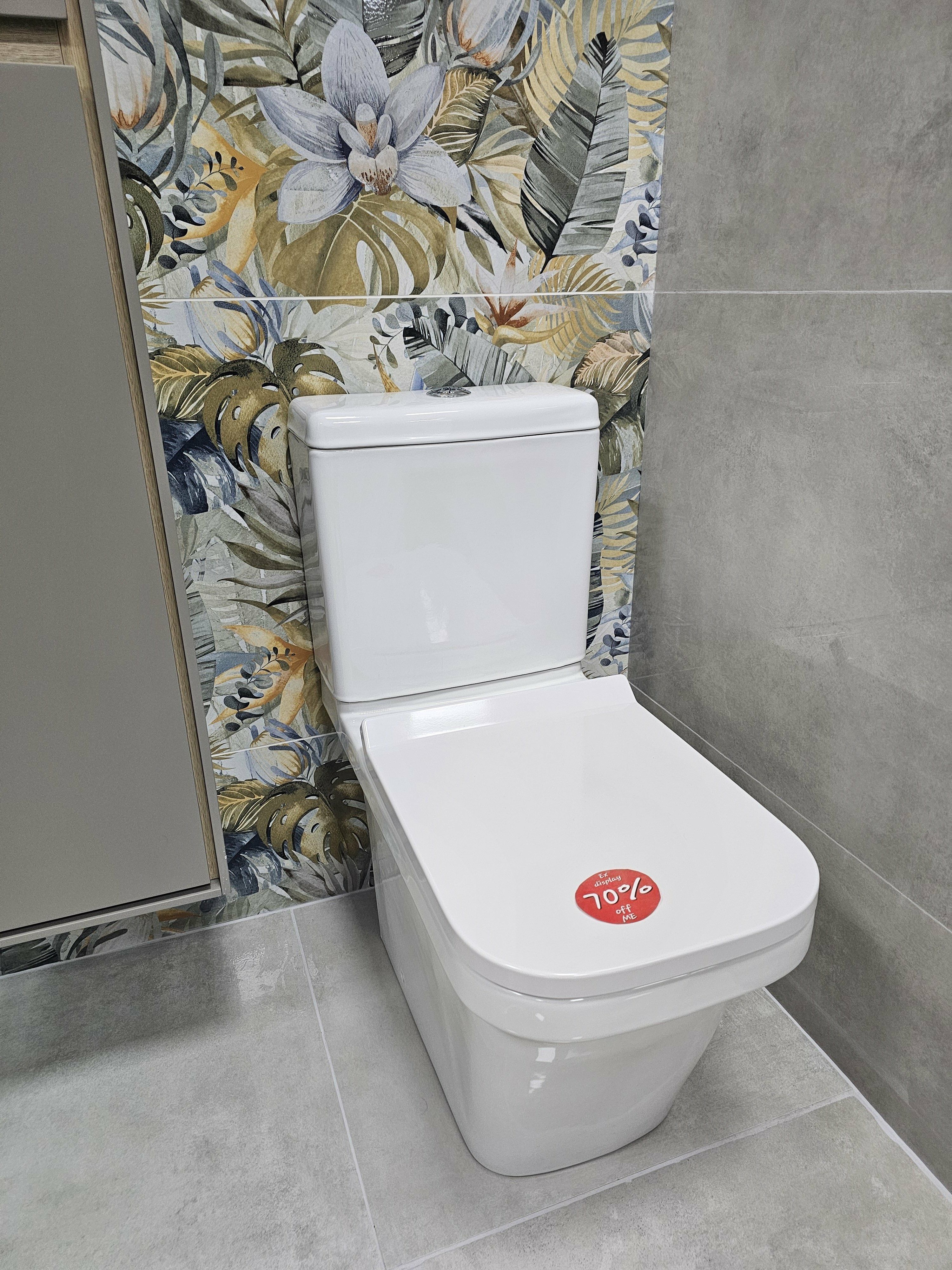 White ex-display toilet displayed against patterned and grey bathroom wall tiles at the Folkestone showroom.