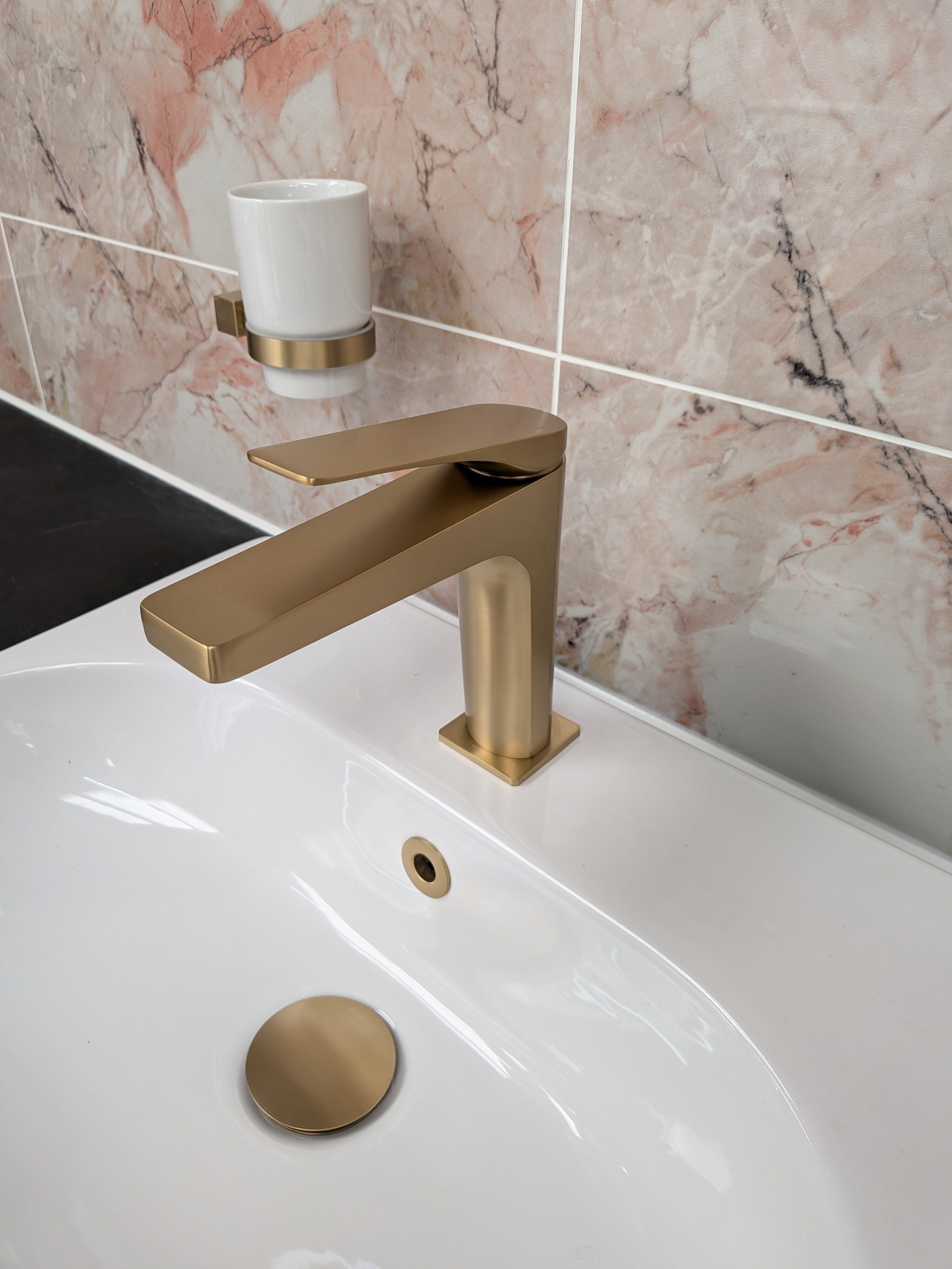 Close-up of a Riven brushed gold basin tap and waste fitted to a white basin at Easy Bathrooms Rayleigh.