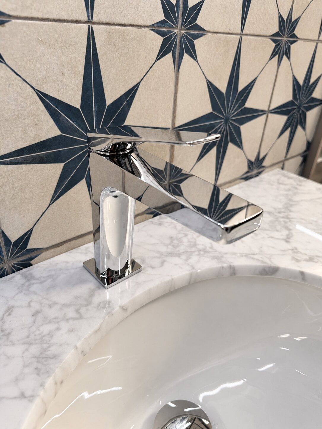 Bathroom tap and basin display at Easy Bathrooms St Albans with patterned blue and white wall tiles.
