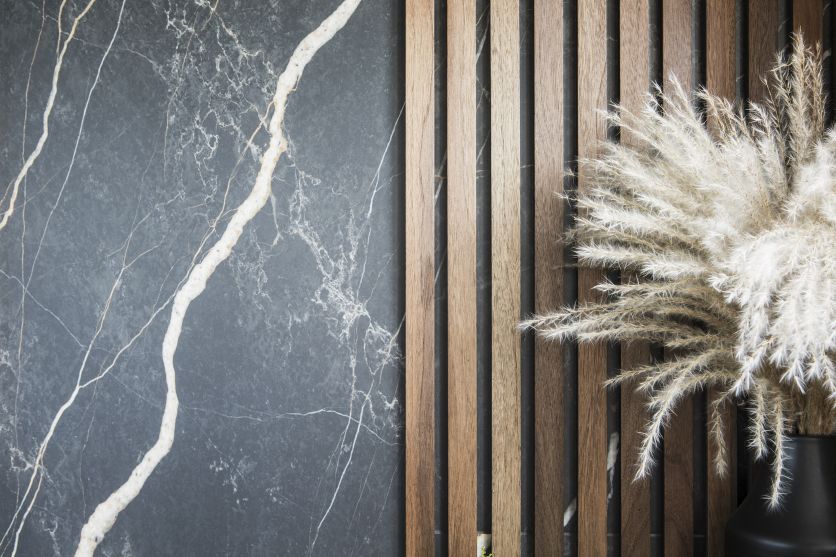 A sophisticated bathroom feature wall showcasing large-format charcoal marble-effect tiles with white veining, seamlessly integrated with vertical natural oak wood slats