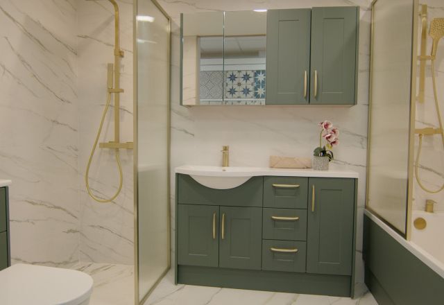 Showroom bathroom furniture display featuring sage green bathroom furniture and gold metallic hardware
