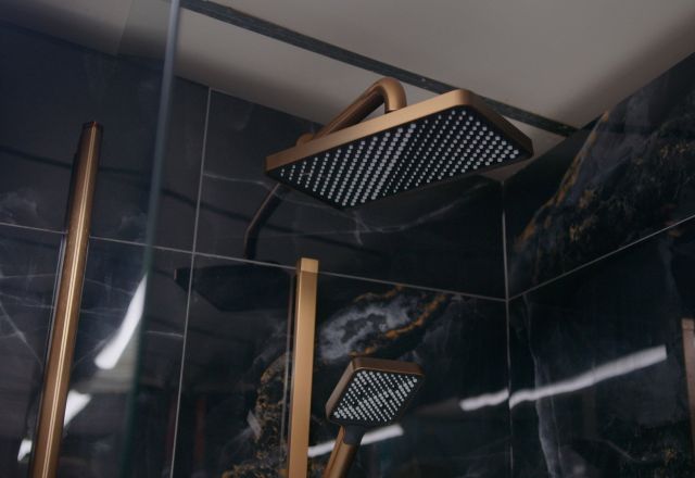 Bathroom furniture display in Easy Bathrooms showroom featuring copper shower and black tiles