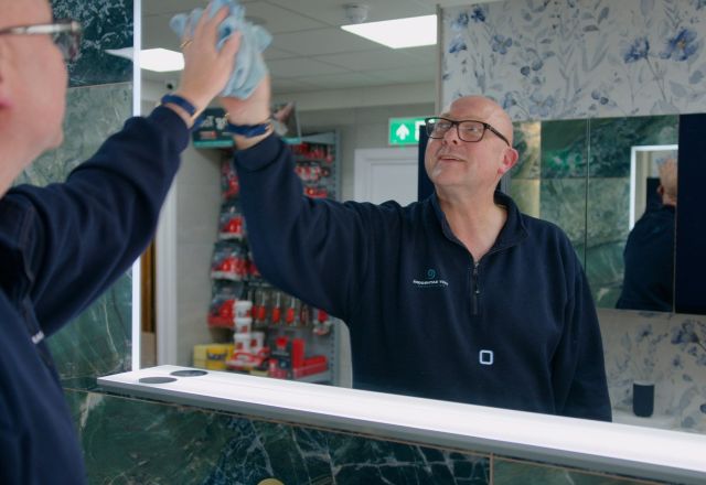 Customer service assistant at Easy Bathrooms Newcastle Airport cleaning mirror display