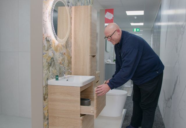 Sales assistant at Easy Bathrooms Newcastle Airport demonstrating how the bathroom vanity unit on display opens