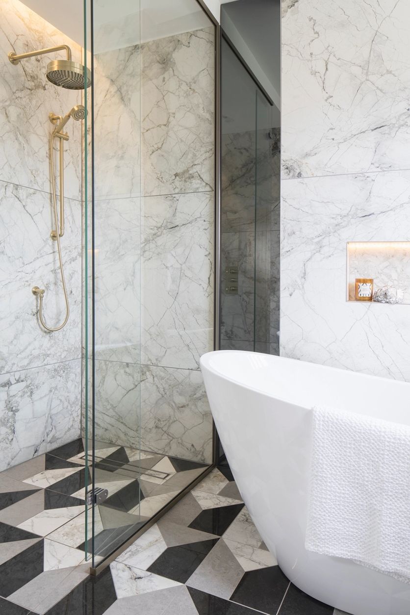 Luxury bathroom featuring marble-effect wall tiles, brushed gold concealed shower, walk-in glass screen and modern freestanding bath.