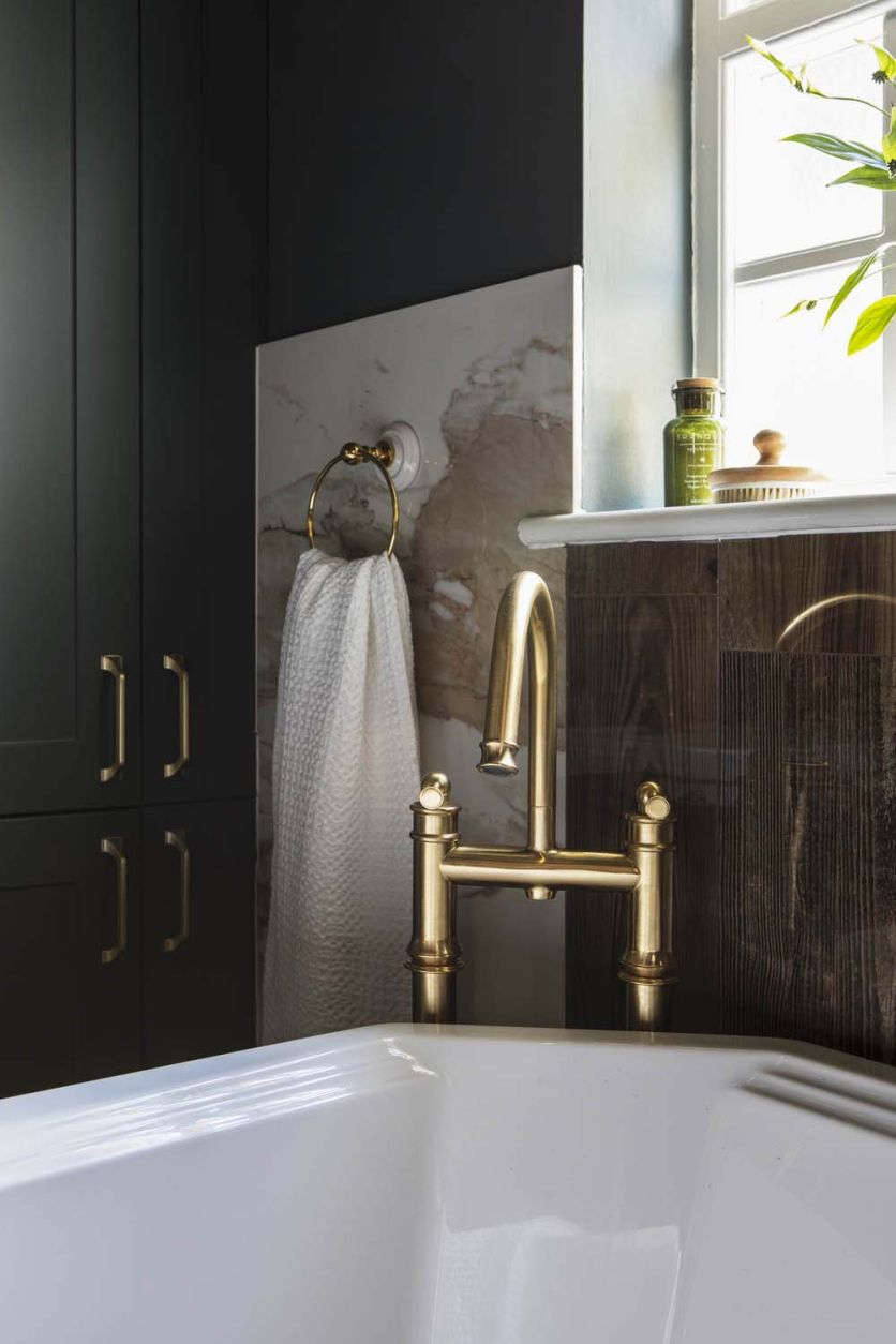 Rainford antique gold bath filler tap mounted over a traditional white bath with Charlie Beige tiles.