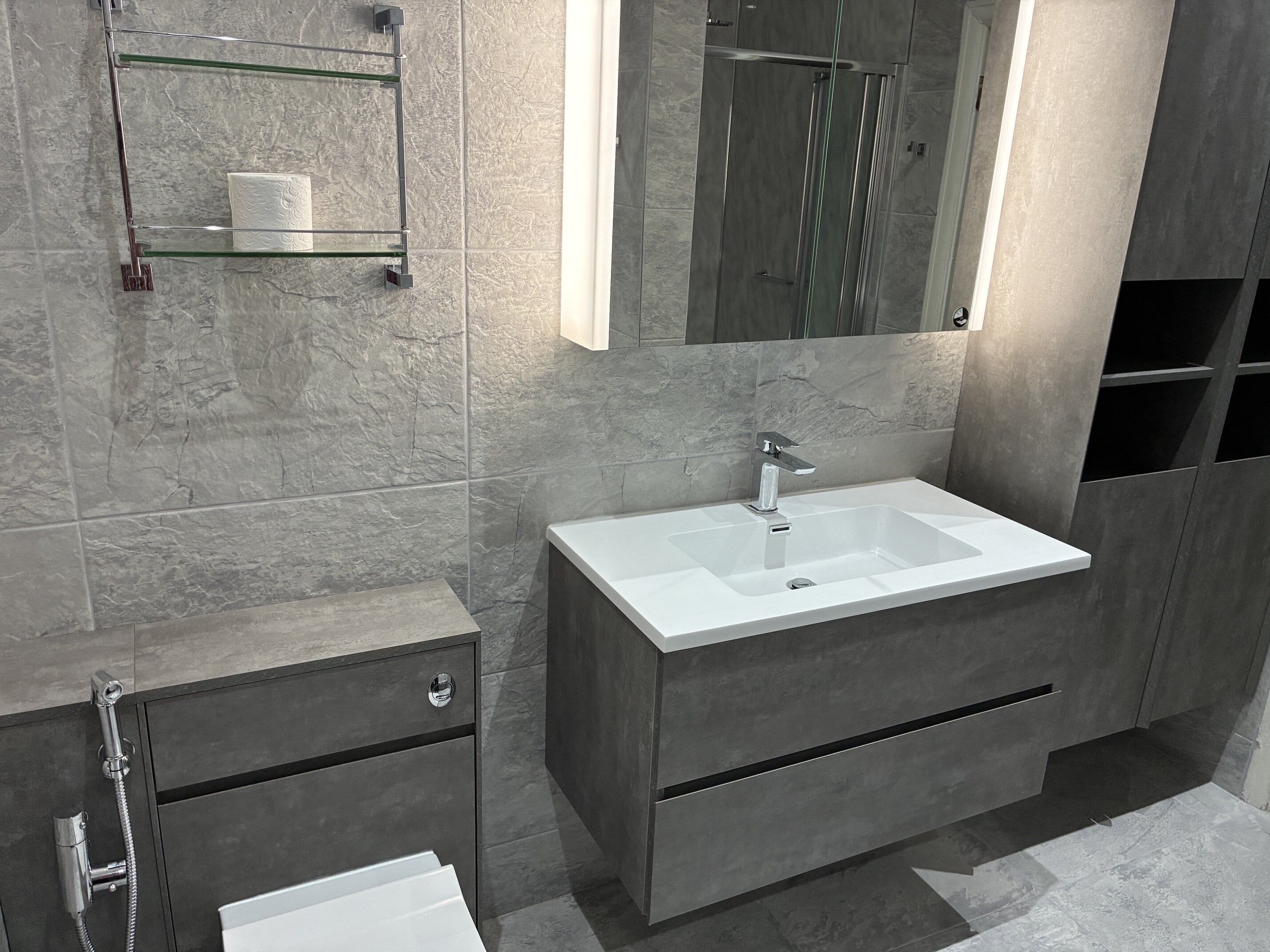Alternative view of the completed grey vanity unit, basin, mirror and bathroom storage.