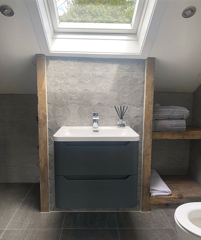 Loft bathroom with charcoal wall hung vanity, grey textured feature tiles and wooden shelving.