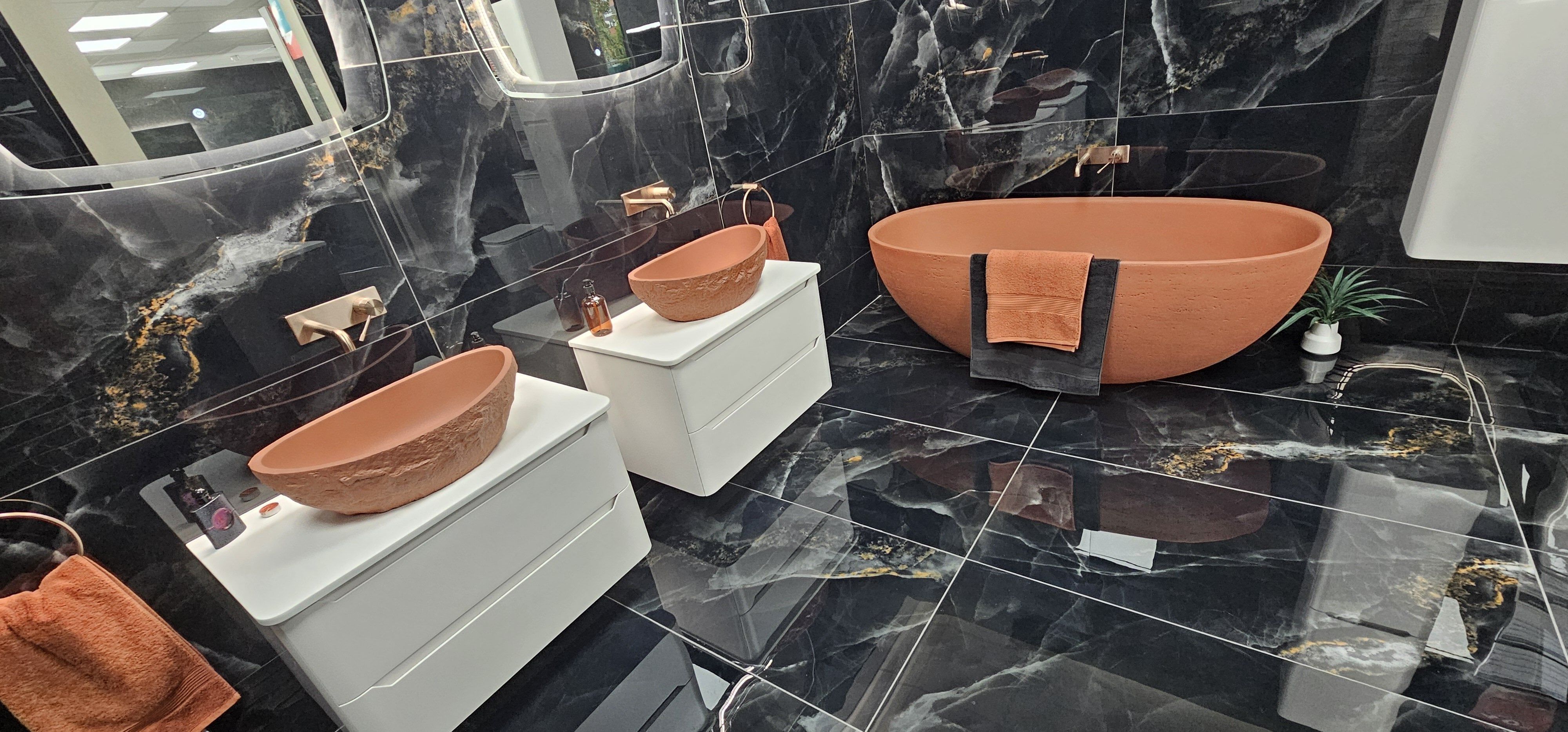 Luxurious bathroom set up with free standing bath, counter top basins and black marble tiles
