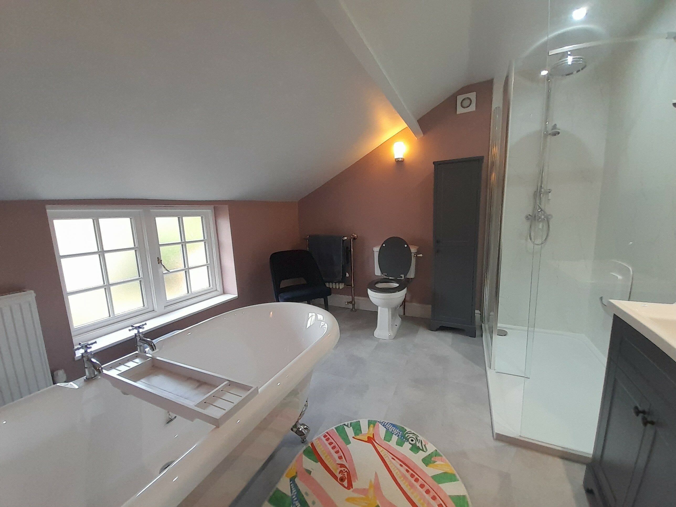 Completed bathroom showing the freestanding bath, enclosed shower and traditional-style finishes.