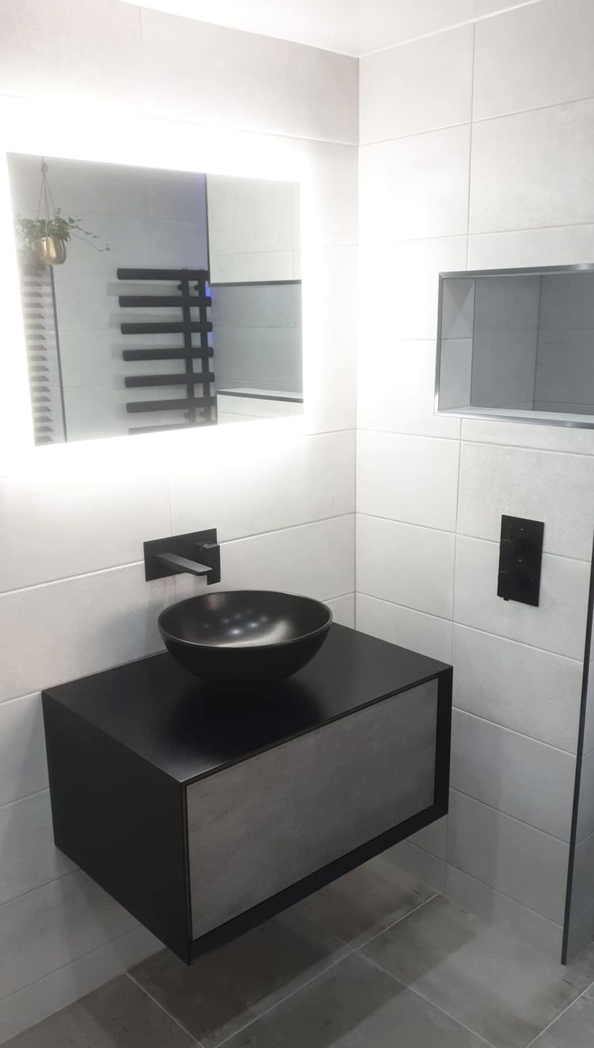 Modern bathroom with a black bowl basin, wall-hung vanity, LED mirror and concrete-effect tiles for a sleek monochrome look.