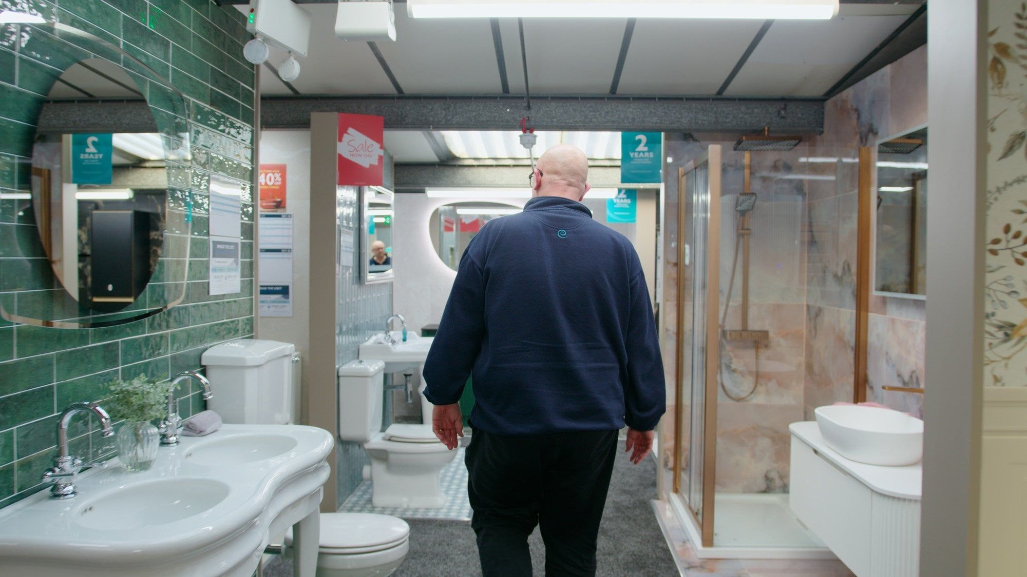 Sales assistant walking through bathroom furniture displays at Easy Bathrooms Newcastle Airport