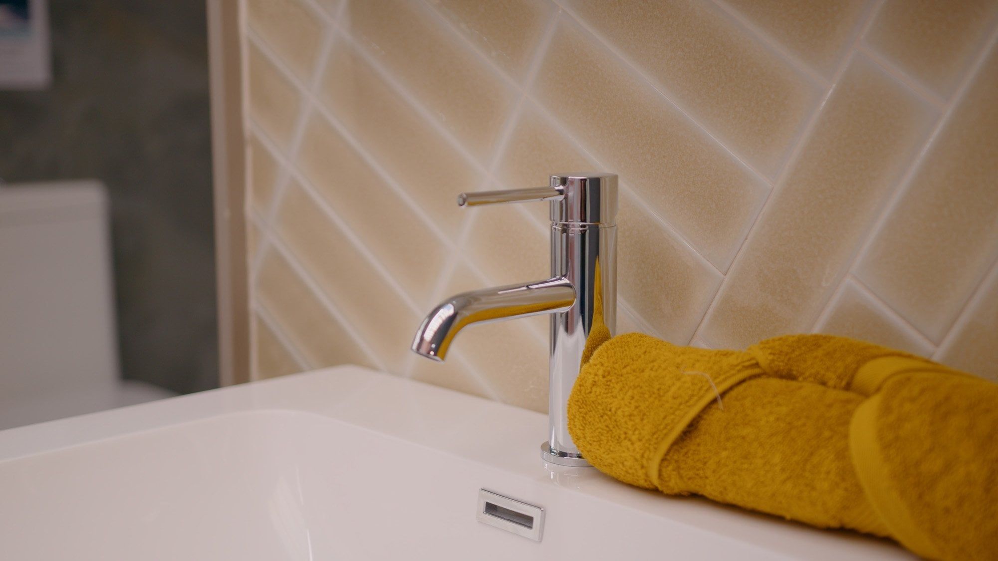 Showroom display of bathroom furniture and tiles in warm yellow tones