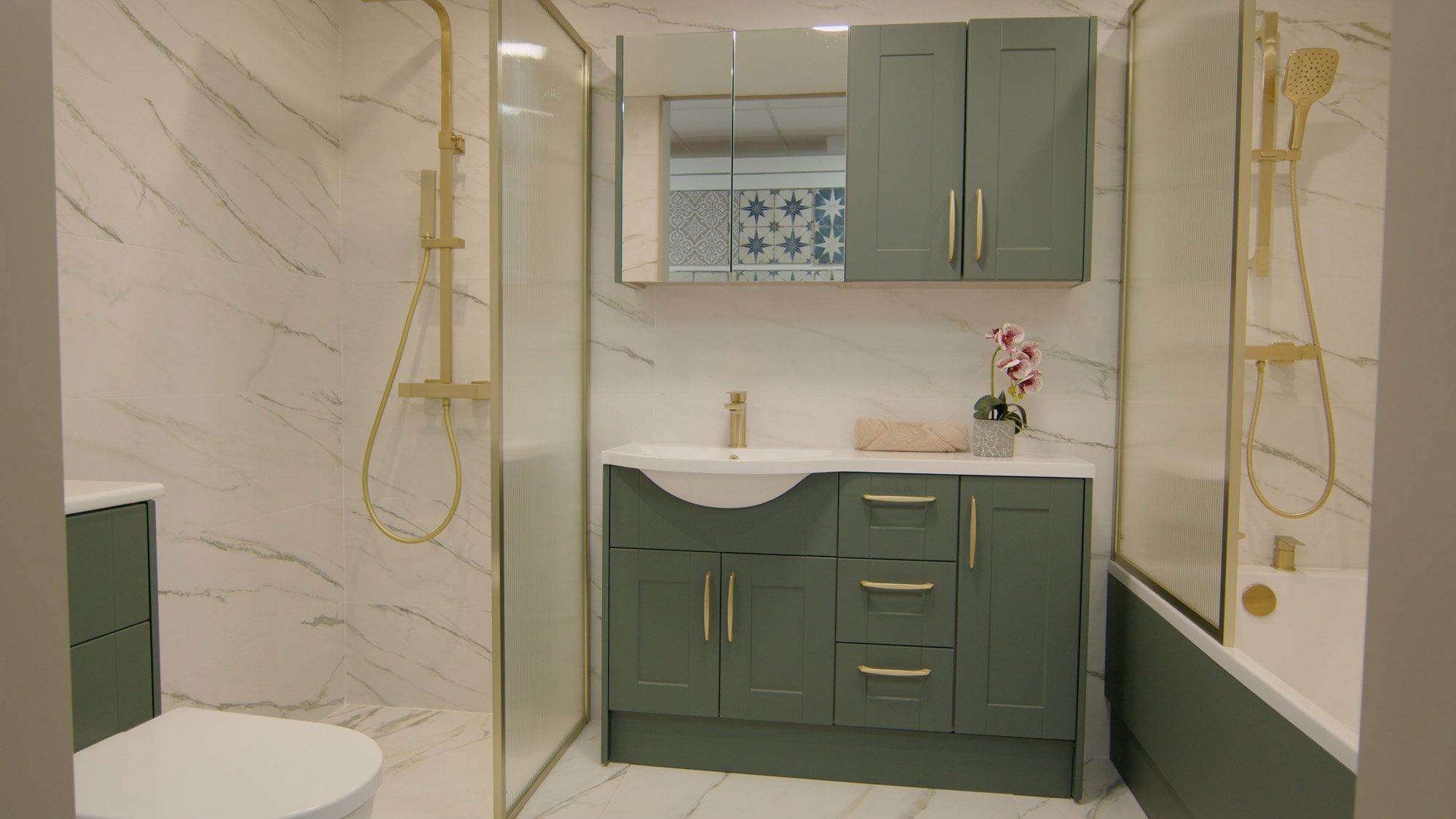 Showroom bathroom furniture display featuring sage green bathroom furniture and gold metallic hardware