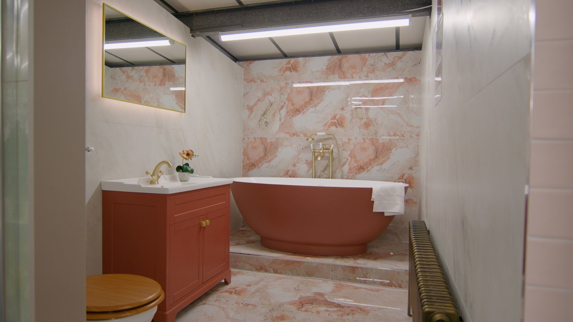 Showroom bathroom furniture display with pink marble tiles and terracotta bath and furniture