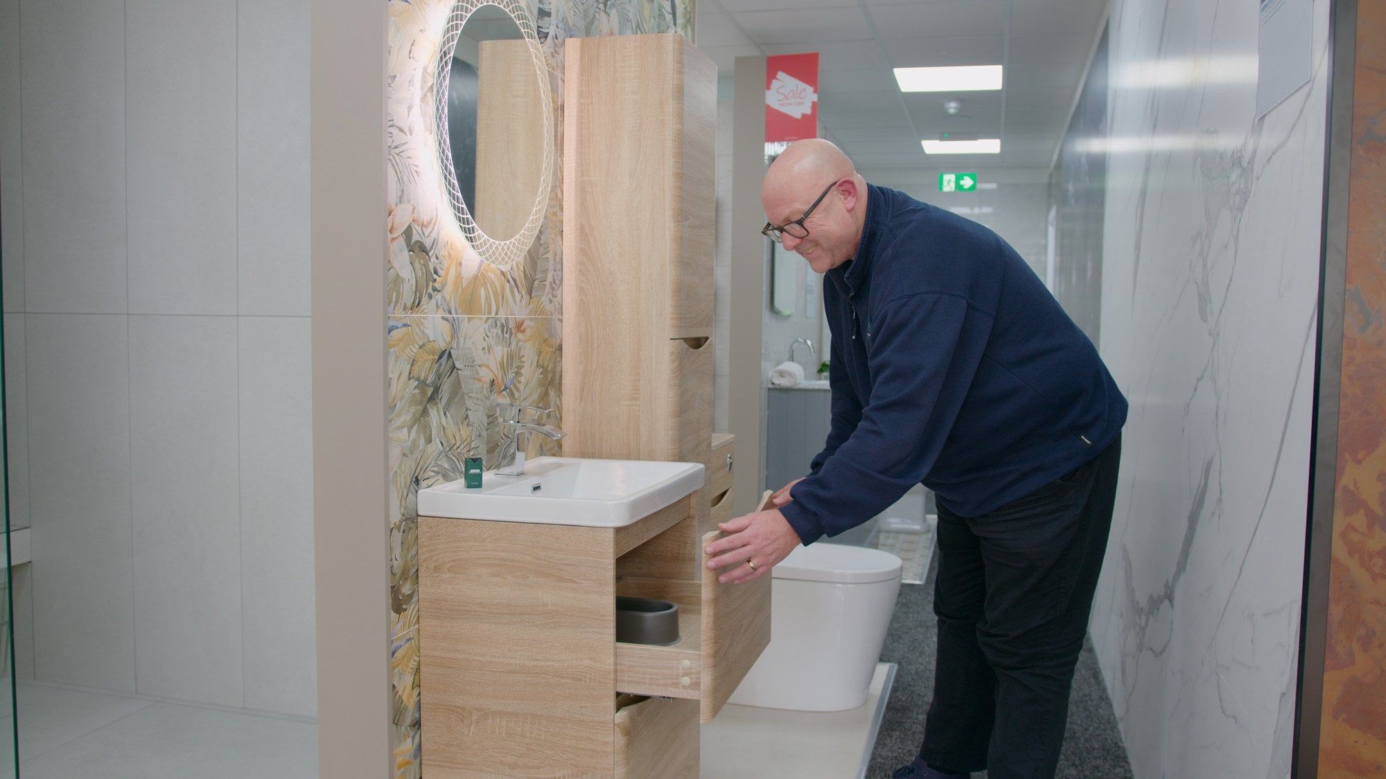 Sales assistant at Easy Bathrooms Newcastle Airport demonstrating how the bathroom vanity unit on display opens