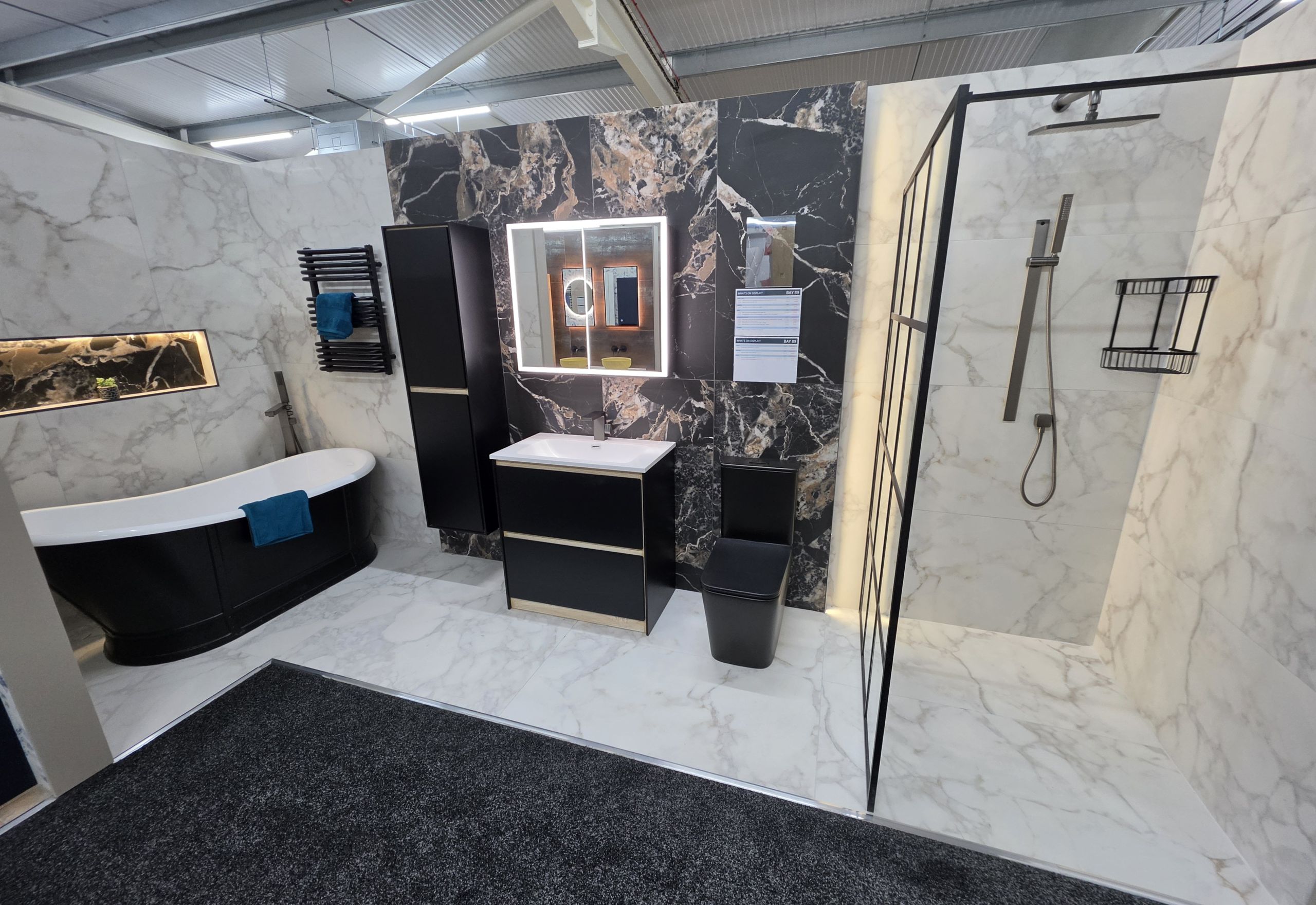 Bathroom display featuring black marble tiles, free standing bath and large shower screen